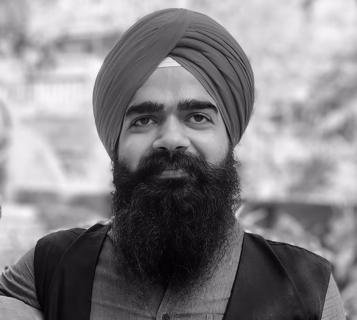 Close-up portrait of a man wearing a turban with a full beard and mustache, smiling slightly.